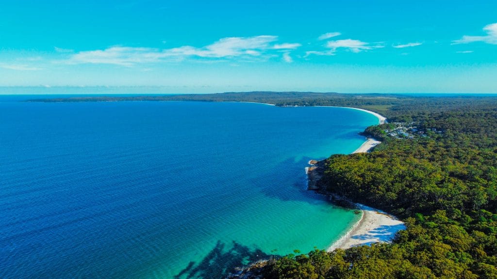 shot of jervis bay showcasing blue and turquoise water, white sandy beaches and bushland