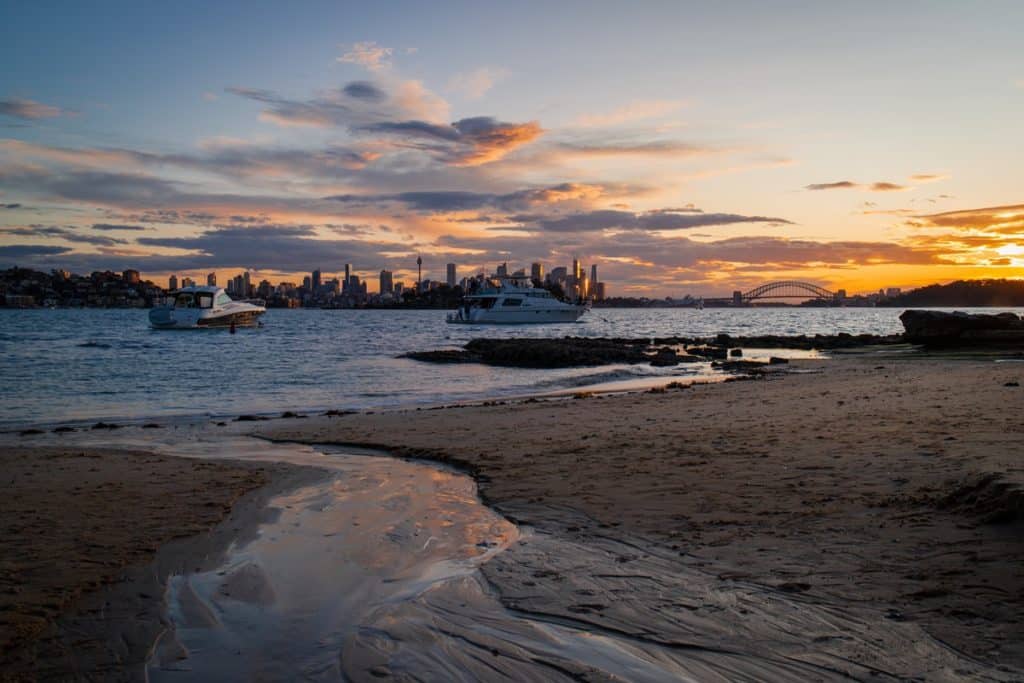 Milk Beach in Sydney at sunset, with the Sydney skyline in the background.