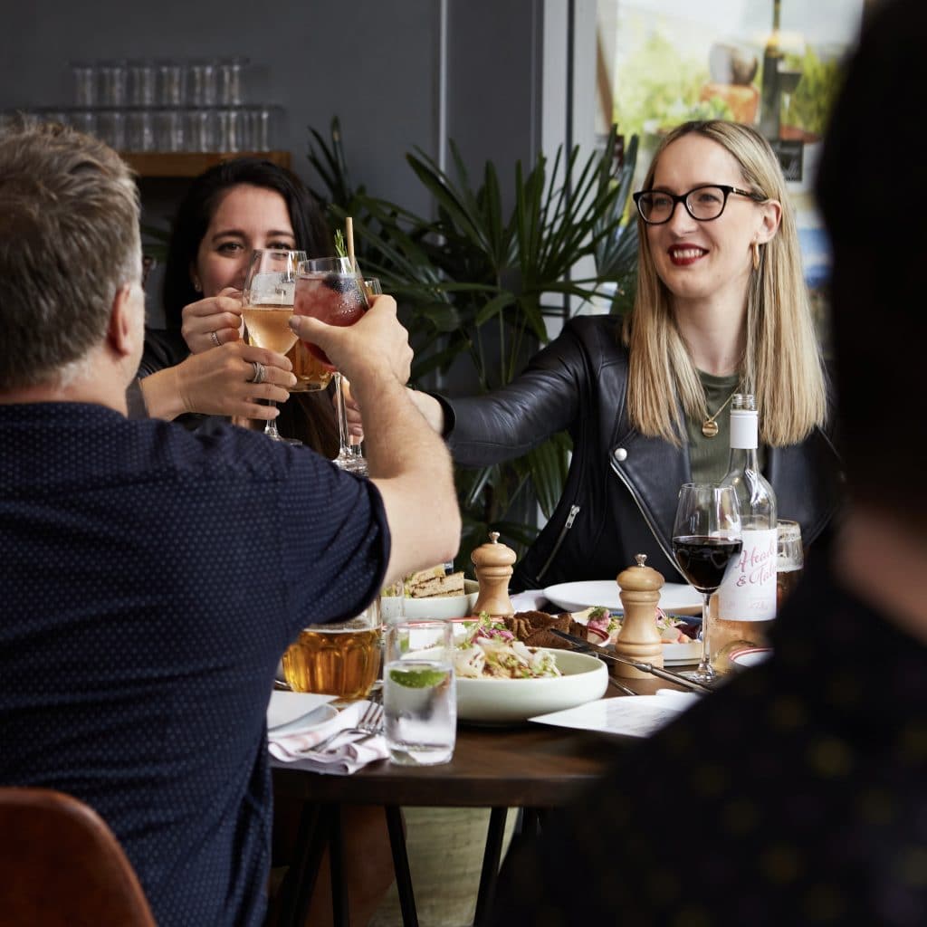 group of people toasting at a table of food and drink