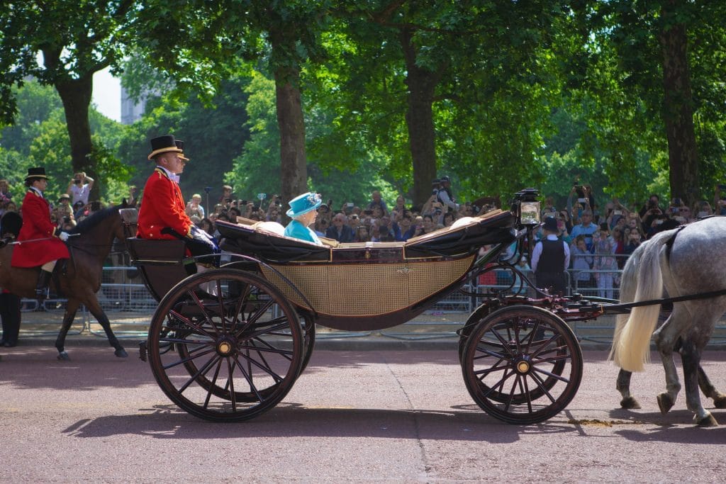 queen elizabeth in a horse drawn carriage, wearing blue