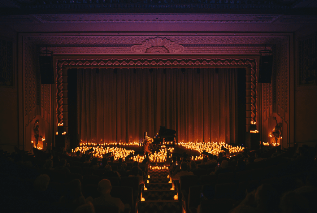 image of stage illuminated by candlelight and pianist performing