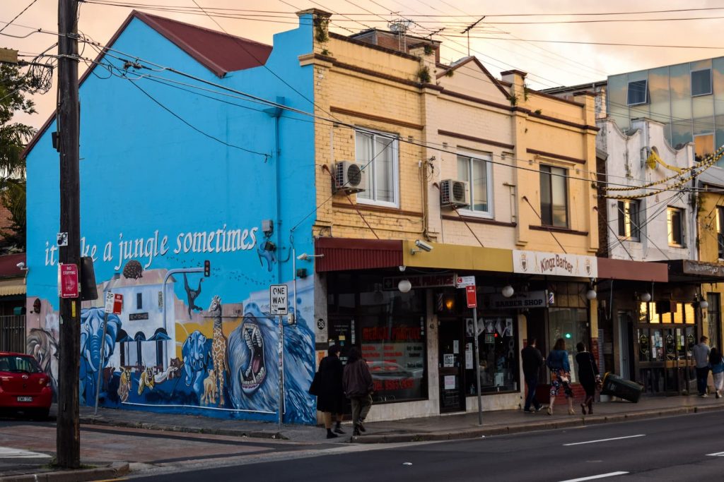 image of a corner with street art mural on one side and shopfronts on the other