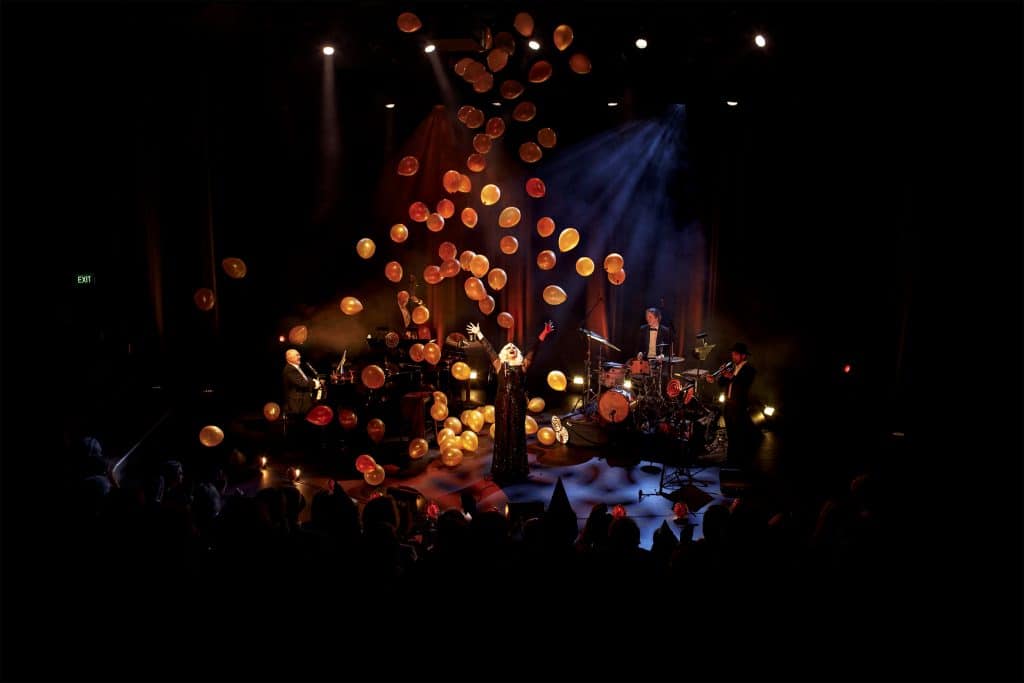 golden baloons falling onto the stage on top of singer and band 