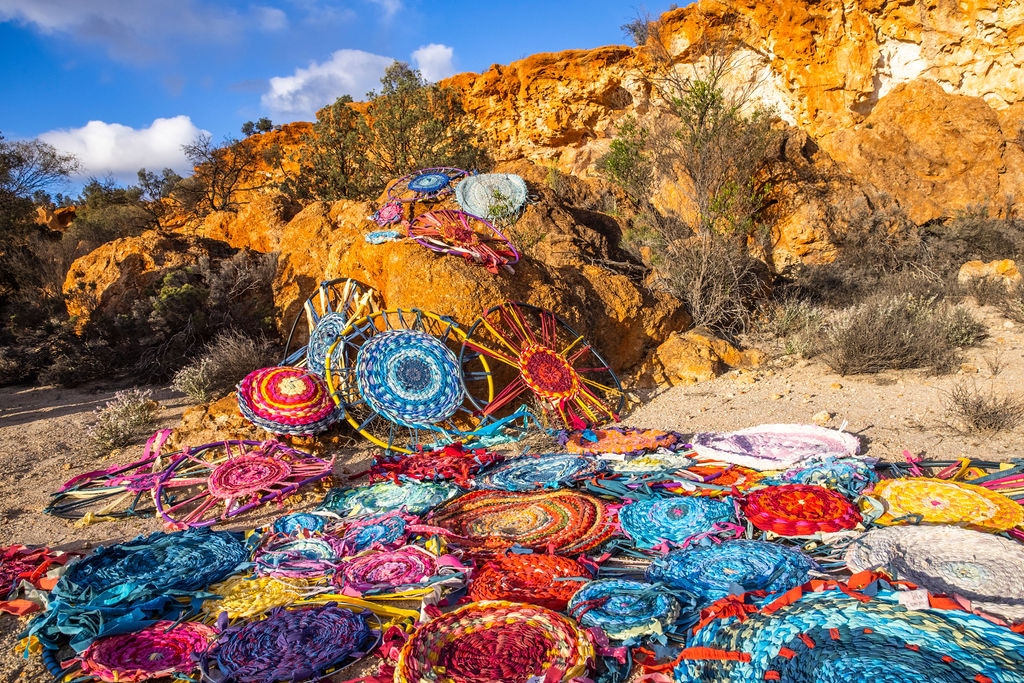 tens of handmade colourful rag rugs laid out on the floor in the outback