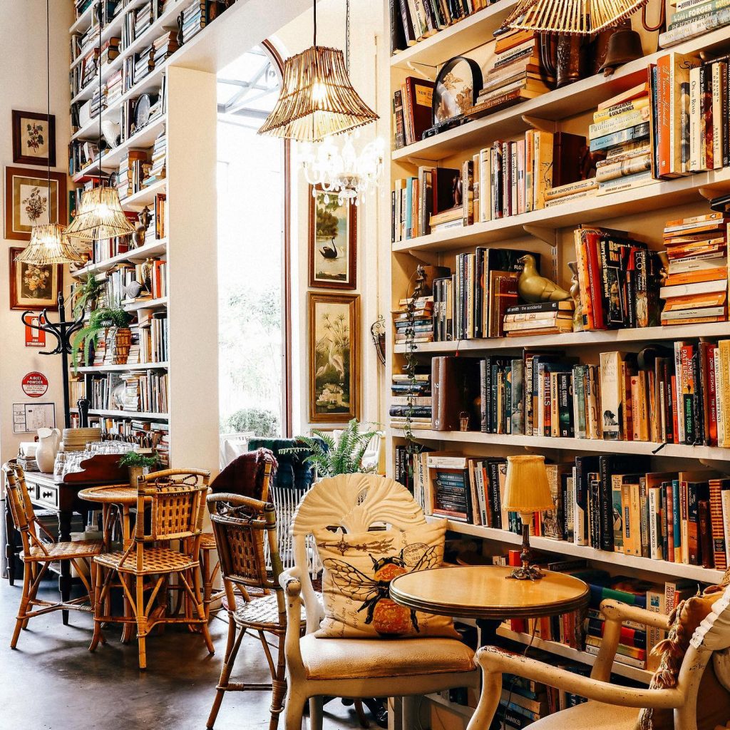 inside of a cafe showing rustic furniture and huge bookcase that takes up the entire wall