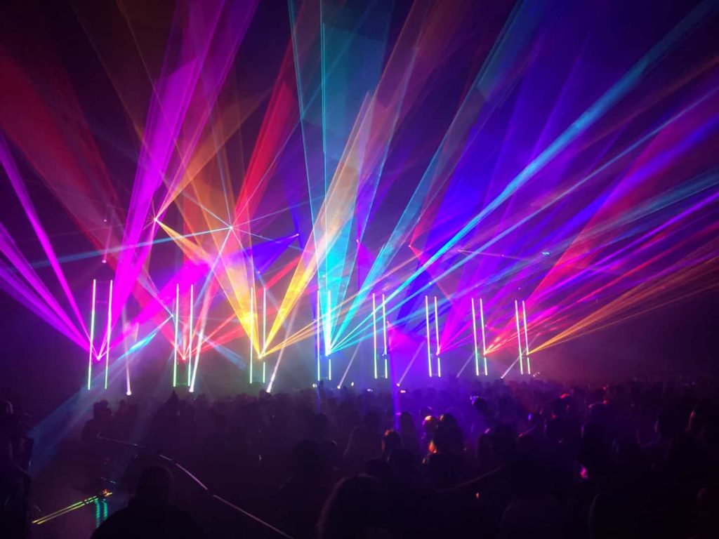 multicoloured light beams on stage projection out over the audience