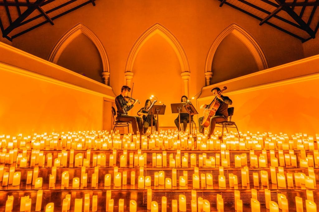 string quartet on stage performing surrounded by candles