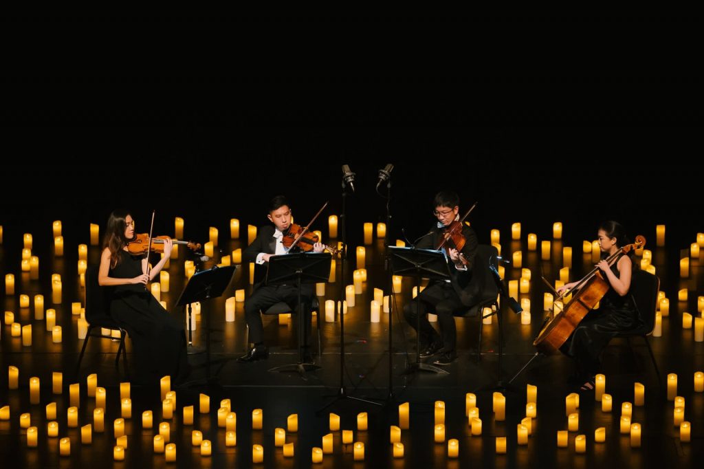 string quartet on darkened stage illuminated only by candles
