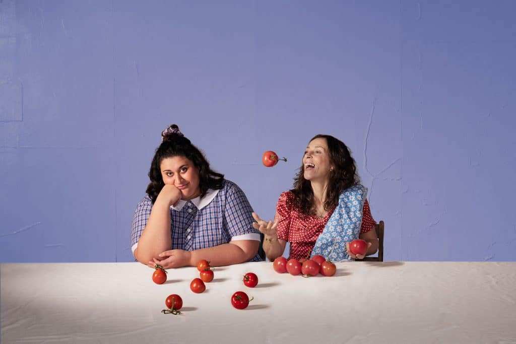 promo shot of looking for alibrandi stage adaptation with young woman and her mother at a table with a bunch of apples sprawled across it