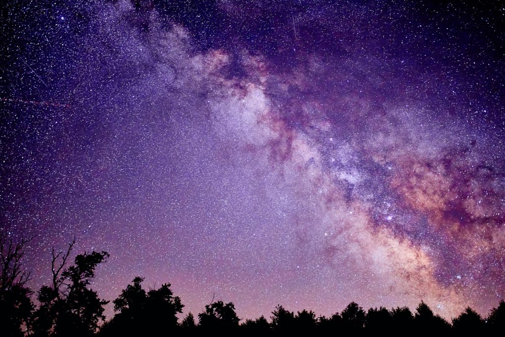 extremely beautiful night sky image of the stars and milky way lit up with a purple glow