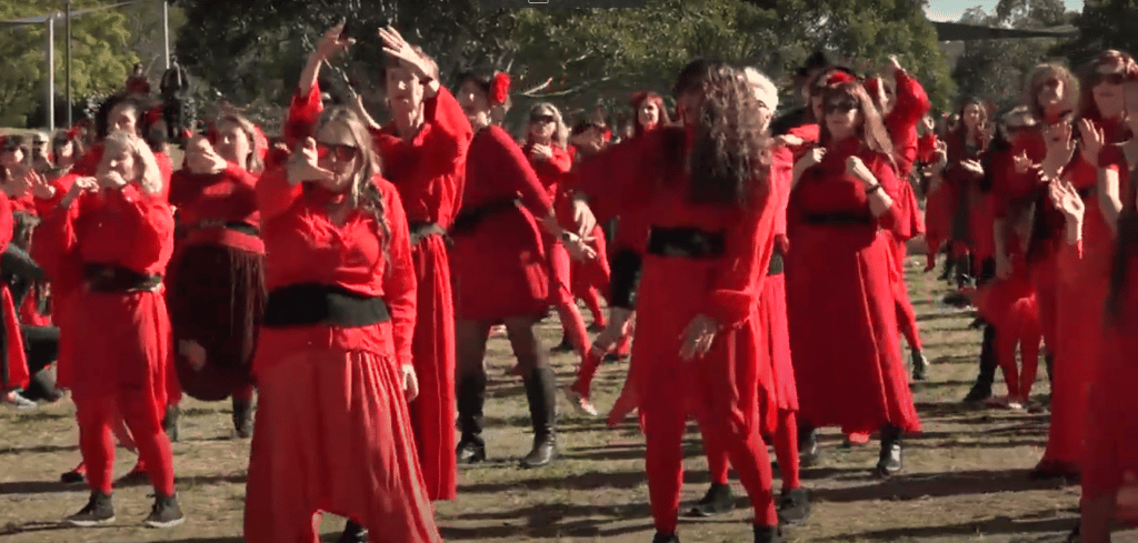 video still of kate bush fans dressed in red and dancing to wuthering heights