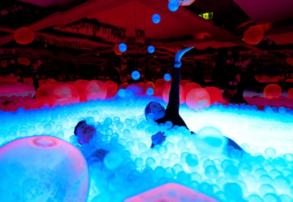 adults plahing in neon ball pit at chaos lab