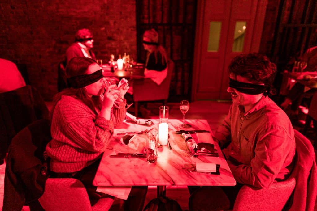 guests blindfolded in a dark room for a dining in the dark experience