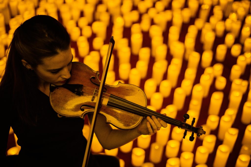 violinist performing in front of hundreds of candles