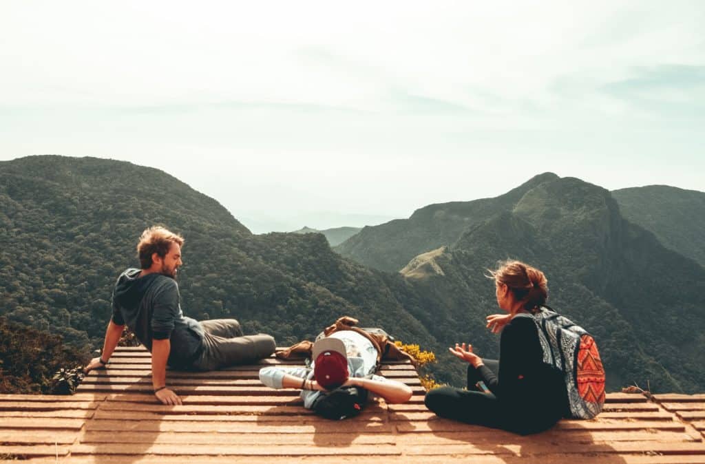three friends sitting at a lookout overlooking mountain range