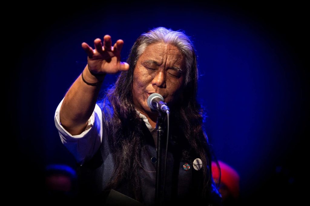 singer-songwriter and multiinstrumentalist tenzin Choegyal singing at a stand up microphone