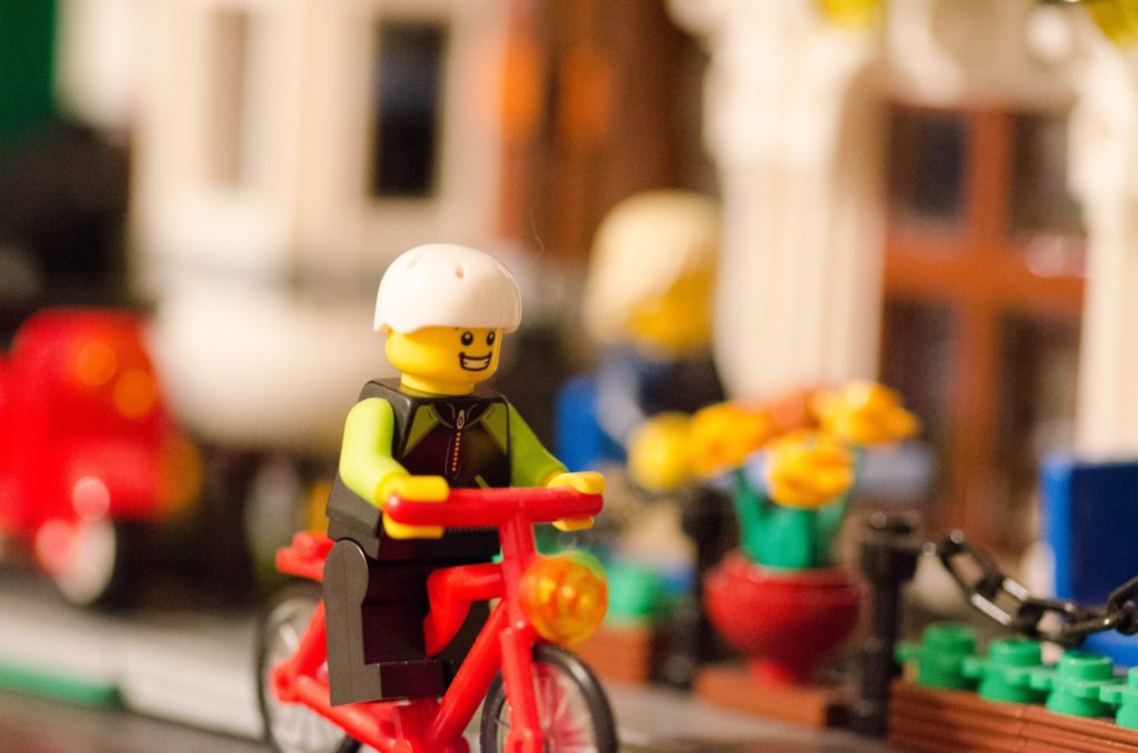 close up lego figure on bike on city street