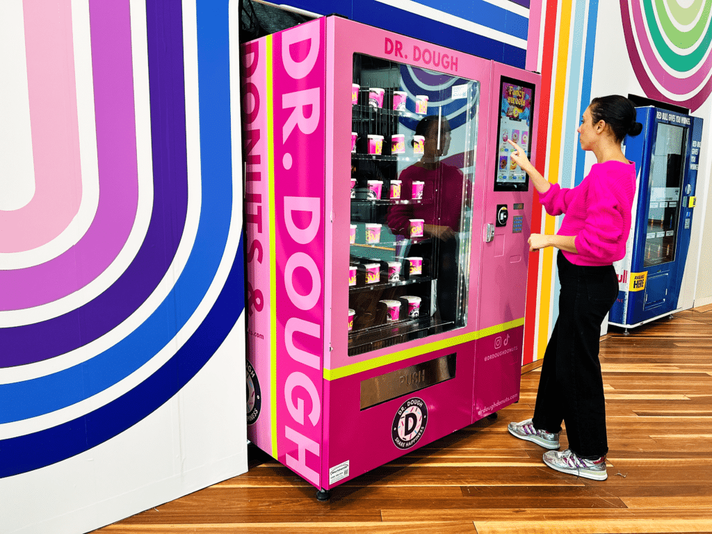 a girl using a donut vending machine