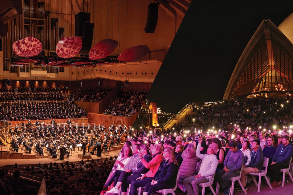 people gathered at the concert hall in the sydney opera house. some people are sitting outside at the forecourt