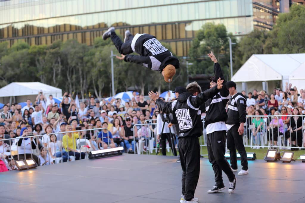k-pop performers dancing on stage while a crowd of people watch them perform