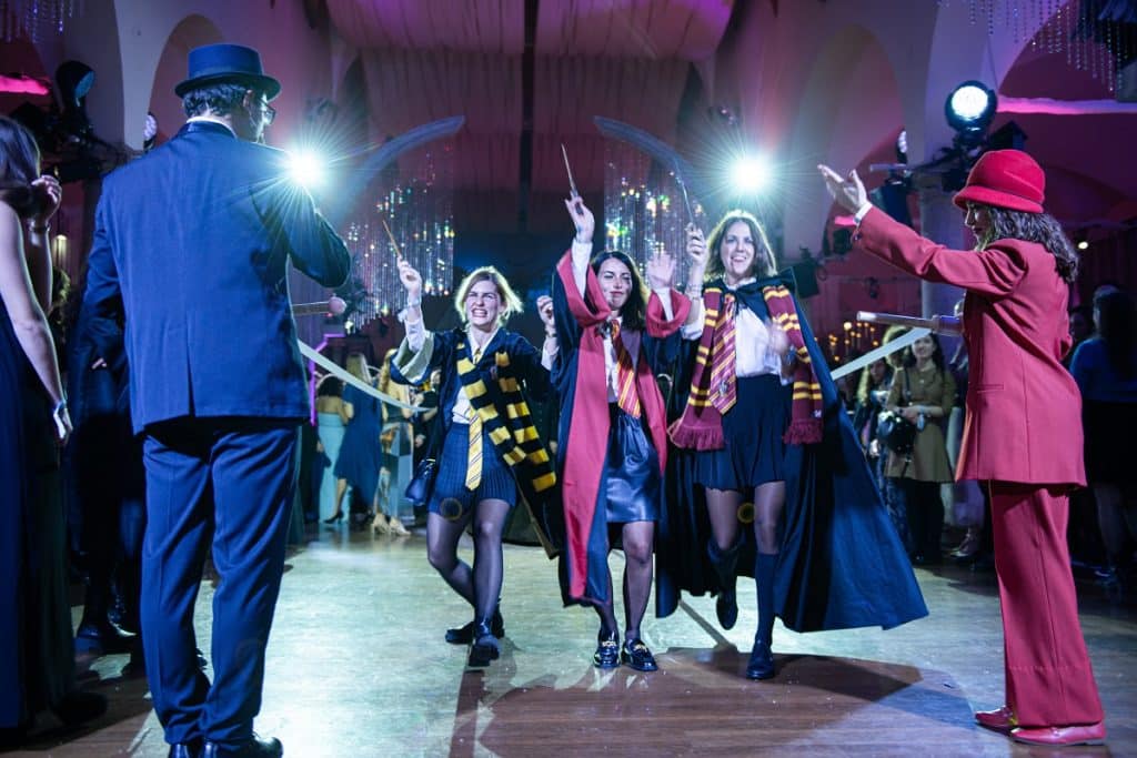 Three women dressed as Hogwarts students at a Yule Ball event.