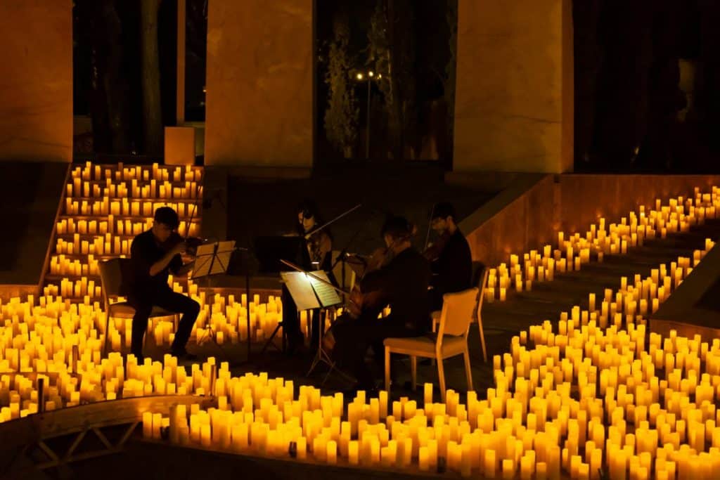 A string quartet performing on stage surrounded by hundreds of candles