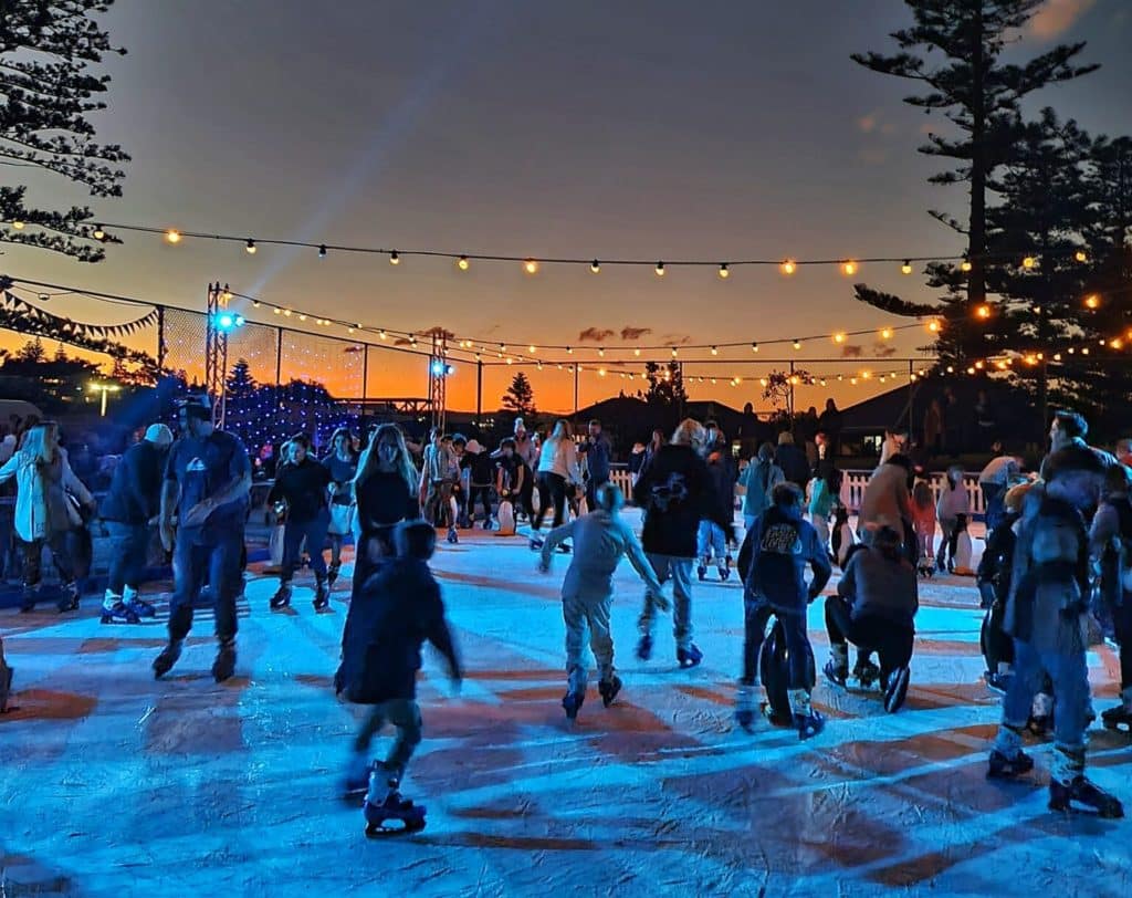 kids and adults ice skating under fairy lights