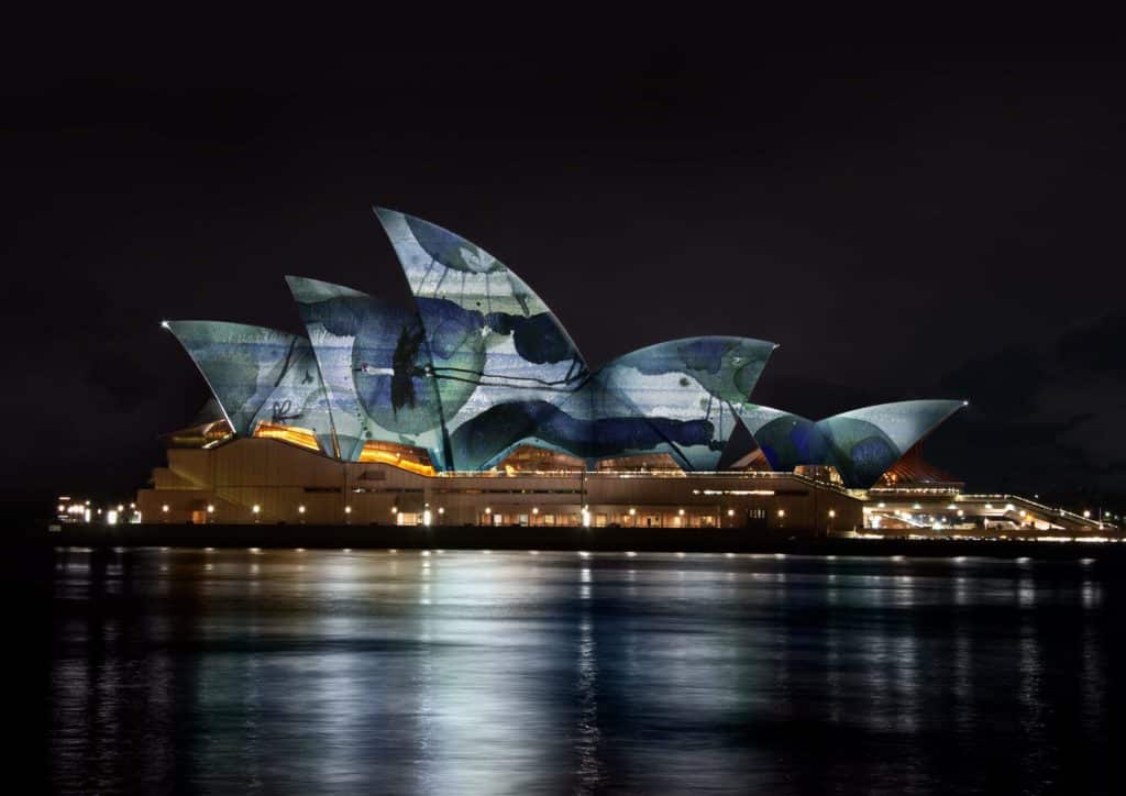 Sydney Opera House's sails lit up in green with artworks by john olsen