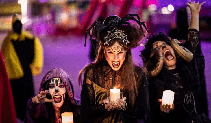 A group of people in halloween clothing holding candles